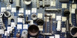 Das Bild zeigt eine Wand, die mit einem blauen Lochblech bedeckt ist, an dem verschiedene mechanische Bauteile und Werkzeuge befestigt sind.