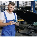 Ein Mitarbeiter in einer Werkstatt bestellt über das Smartphone Ersatzteile.