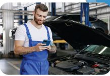 Ein Mitarbeiter in einer Werkstatt bestellt über das Smartphone Ersatzteile.