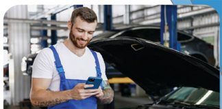 Ein Mitarbeiter in einer Werkstatt bestellt über das Smartphone Ersatzteile.