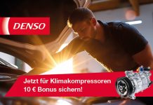 Ein Werkstattmitarbeiter arbeitet bei Tageslicht am geöffneten Motorraum eines Fahrzeugs. Die Szene vermittelt professionellen Klimaservice in einer modernen Kfz Werkstatt während der Sommersaison.